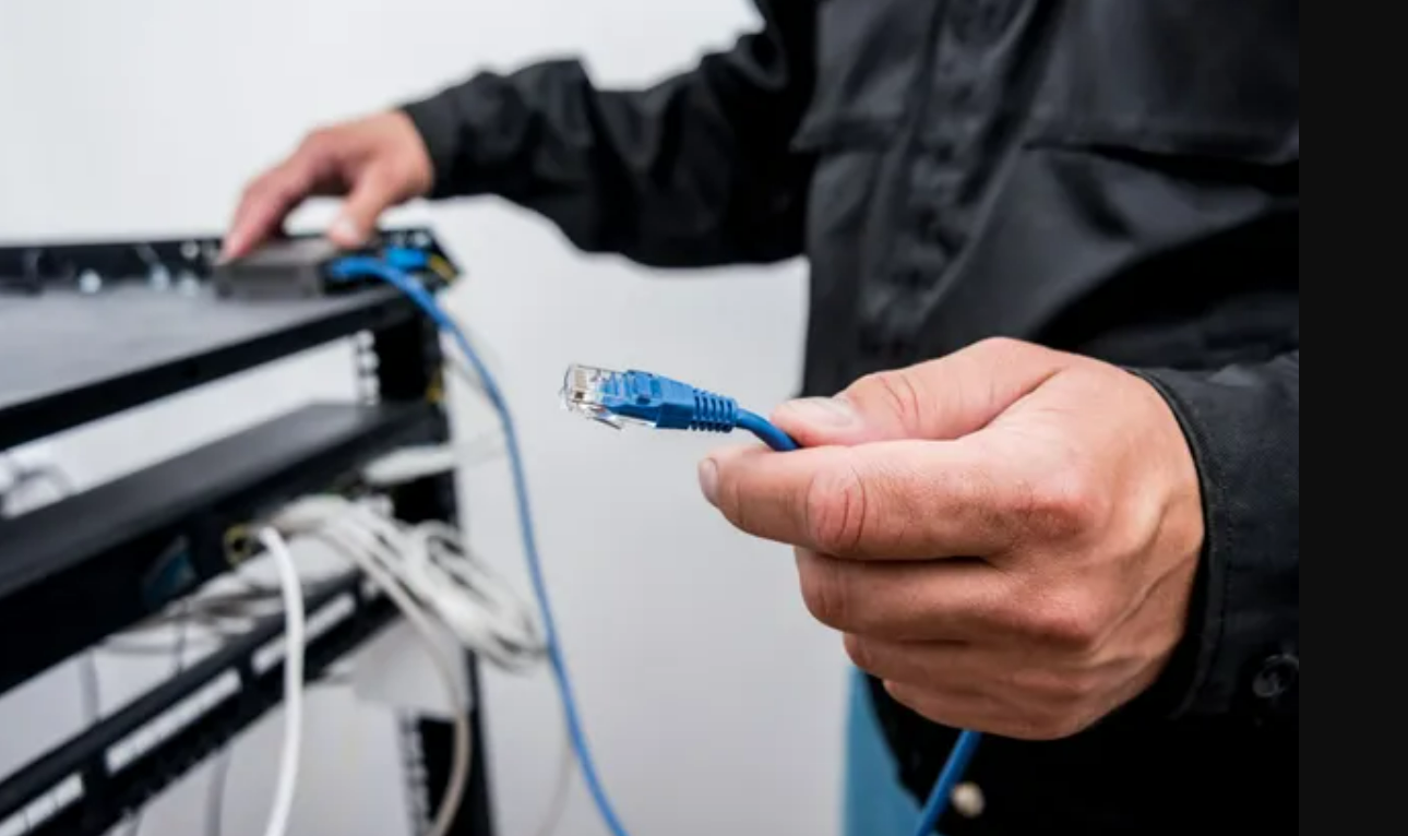 a cable installer carefully setting up equipment in a residential home. The installer is wearing a safety helmet and a company-branded uniform, surrounded by tools and cables. This image represents the services offered by Insurance Company Grove City, specifically focusing on providing tailored insurance solutions for cable installation professionals.